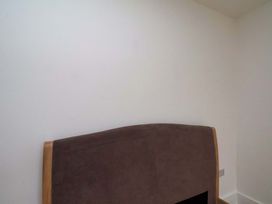 A bedroom with a headboard and a white wall at Beachwalk Villa 2 in Whitby