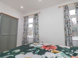 A bedroom with a wardrobe and floral curtains at Beachwalk Villa 2 in Whitby