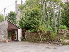 An exterior view of a building with plants and a stone wall at Lannlyvri Lodge in Lanlivery near Lostwithiel