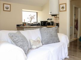 A living room with a sofa and kitchen area at Lannlyvri Lodge Lanlivery near Lostwithiel