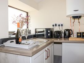A kitchen with a sink, wine bottle, and microwave at Lannlyvri Lodge in Lanlivery near Lostwithiel