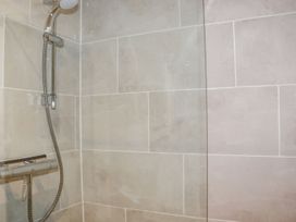 A shower area with tiled walls and a glass panel at Lannlyvri Lodge in Lanlivery near Lostwithiel