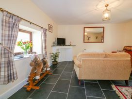 A living room with a television and a rocking horse at Camellia Cottage in Bodmin