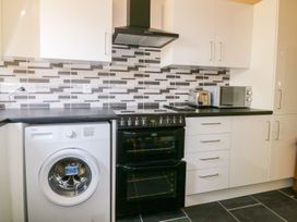 A kitchen with appliances including a washing machine, oven, and microwave at Camellia Cottage in Bodmin