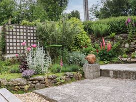 A garden with flowers and stone features at Camellia Cottage in Bodmin