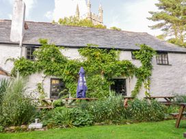 A cottage with green plants and benches at Camellia Cottage in Bodmin