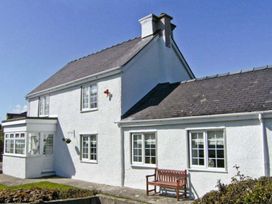 A white house with windows and a bench at Tyddyn Gyrfa Cottage, Cemaes Bay