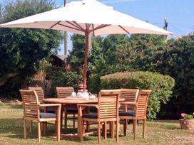 A garden with a table and chairs under an umbrella at Tyddyn Gyrfa Cottage Cemaes Bay