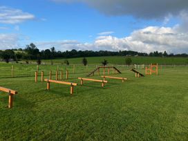 An outdoor area with obstacle course equipment and a grassy field at Coniston (Pet) Penrith
