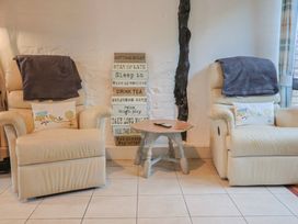 A living room with recliner chairs and a decorative sign at Apple Cottage in Whitchurch Canonicorum