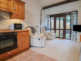 A kitchen with a microwave, oven, and recliner chairs at Apple Cottage Whitchurch Canonicorum