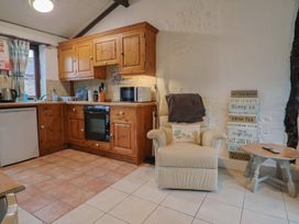 A kitchen with wooden cabinets and appliances at Apple Cottage in Whitchurch Canonicorum