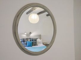 A bedroom with a mirror reflecting pillows and a lamp at Apple Cottage in Whitchurch Canonicorum