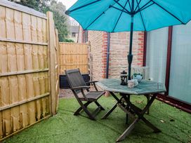 A garden with a table and chair under an umbrella at Apple Cottage Whitchurch Canonicorum