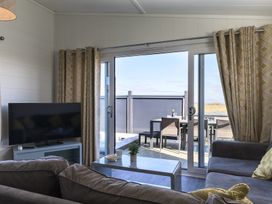 A living room with a television and sliding door at Blencathra Family (Pet) in Penrith