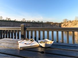 A table with a book and snacks near water at Pods by the Lake in Penrith