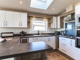 A kitchen with cabinets, sink, stove, and window at Keswick (Pet) Penrith