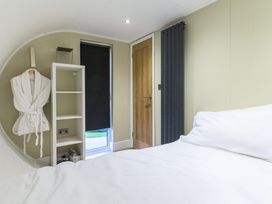 A bedroom with a bed and shelf at Pods by the Lake (Pet) Penrith