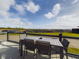 An outdoor deck with a table and chairs at Spa Sauna Lodge Penrith