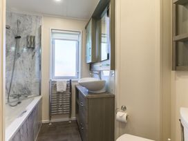 A bathroom with a bathtub, shower, sink and towel rail at Helvellyn (Pet) Penrith