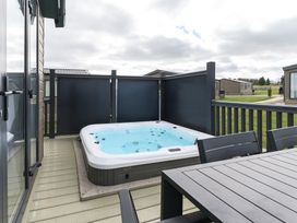 A hot tub on a patio with a table and chairs at Blencathra Spa (Pet) in Penrith