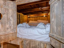 A bed with sheets and blanket in a wooden cabin at Kruger in Penrith