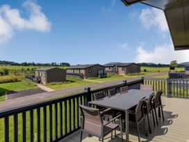 A deck with a table and chairs overlooking cabins at Scaféll in Penrith