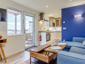 A living room with a sofa and kitchen in Lakeside Studio Pet Portreath