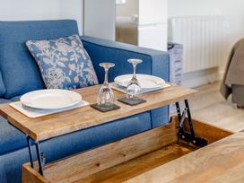 A living room with a sofa and coffee table set for dining at Lakeside Studio Pet Portreath