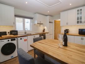 A kitchen with wooden table and appliances at Renes Shop in Grange-Over-Sands