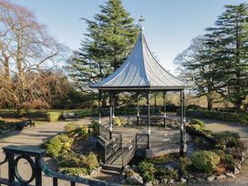 A pavilion in a garden surrounded by benches and trees at Renes Shop in Grange-Over-Sands