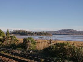 A view of water and land with trees and a fence beside train tracks at Renes Shop in Grange-Over-Sands