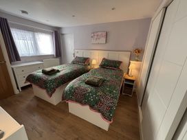 A bedroom with two beds and a bedside table at Drapers Cottage in Cark In Cartmel
