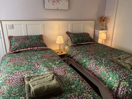 A bedroom with two beds and lamps at Drapers Cottage in Cark In Cartmel