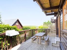 A deck with a wooden table and benches at Scandinavian Lodge 4 in Portreath