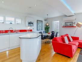 A kitchen with a dining area and red sofa at Signature Lodge Pet 4, Portreath