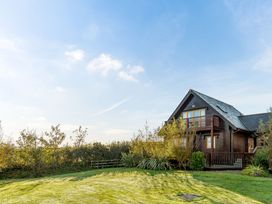 A house with a balcony and surrounding greenery at Scandinavian Hot Tub Lodge in Portreath