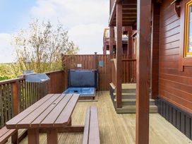 An outdoor area with a hot tub and wooden furniture at Scandinavian Hot Tub Lodge Pet Portreath