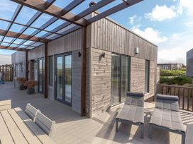 An outdoor area with wooden seating and sliding glass doors at Signature Lodge 6 Portreath