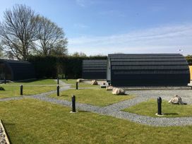 An outdoor area with huts and a grassy pathway at Pod 4 (No Pets) in Carnforth