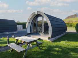 A pod with a table and benches in an outdoor area at Pod 6 (No Pets) in Tewitfield