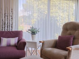 A living room with a sofa, armchair and a table with a plant at Fluta in Seaton