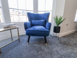 A living room with a blue chair and side table at 2 bed Scarborough