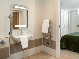 A bathroom with a sink and mirror and a bedroom visible in the background at The School House in Newton Abbot