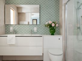 A bathroom with a sink, mirror, and flowers in a vase at The School House in Newton Abbot