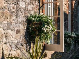 A flower box with white flowers beside a window on a stone wall at The School House in Ashburton