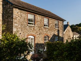 An outdoor view of a stone house with windows and greenery at Upper School House Newton Abbot