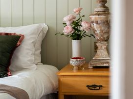 A bedroom with a bed, nightstand, flowers in a vase, and a decorative bowl at Upper School House in Newton Abbot