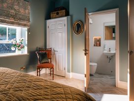 A bedroom with a chair, bed and an adjoining bathroom at Upper School House in Newton Abbot