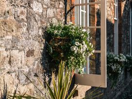 A window with flowers on a stone wall at Upper School House in Newton Abbot